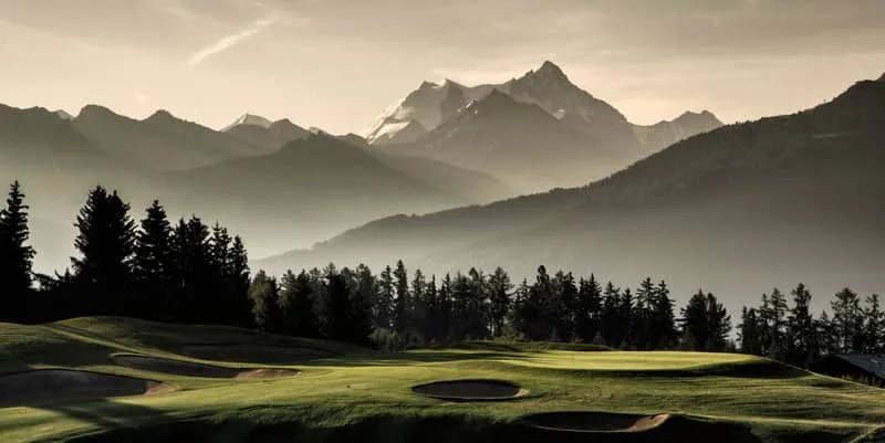 Terrain de golf au coucher du soleil avec montagnes